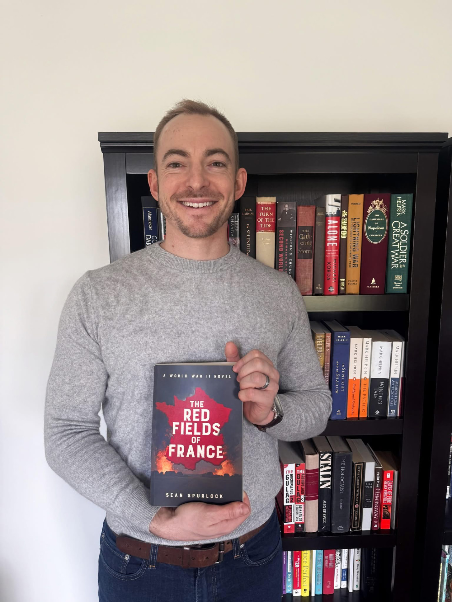 Sean Spurlock holding The Red Fields of France in front of his library shelf